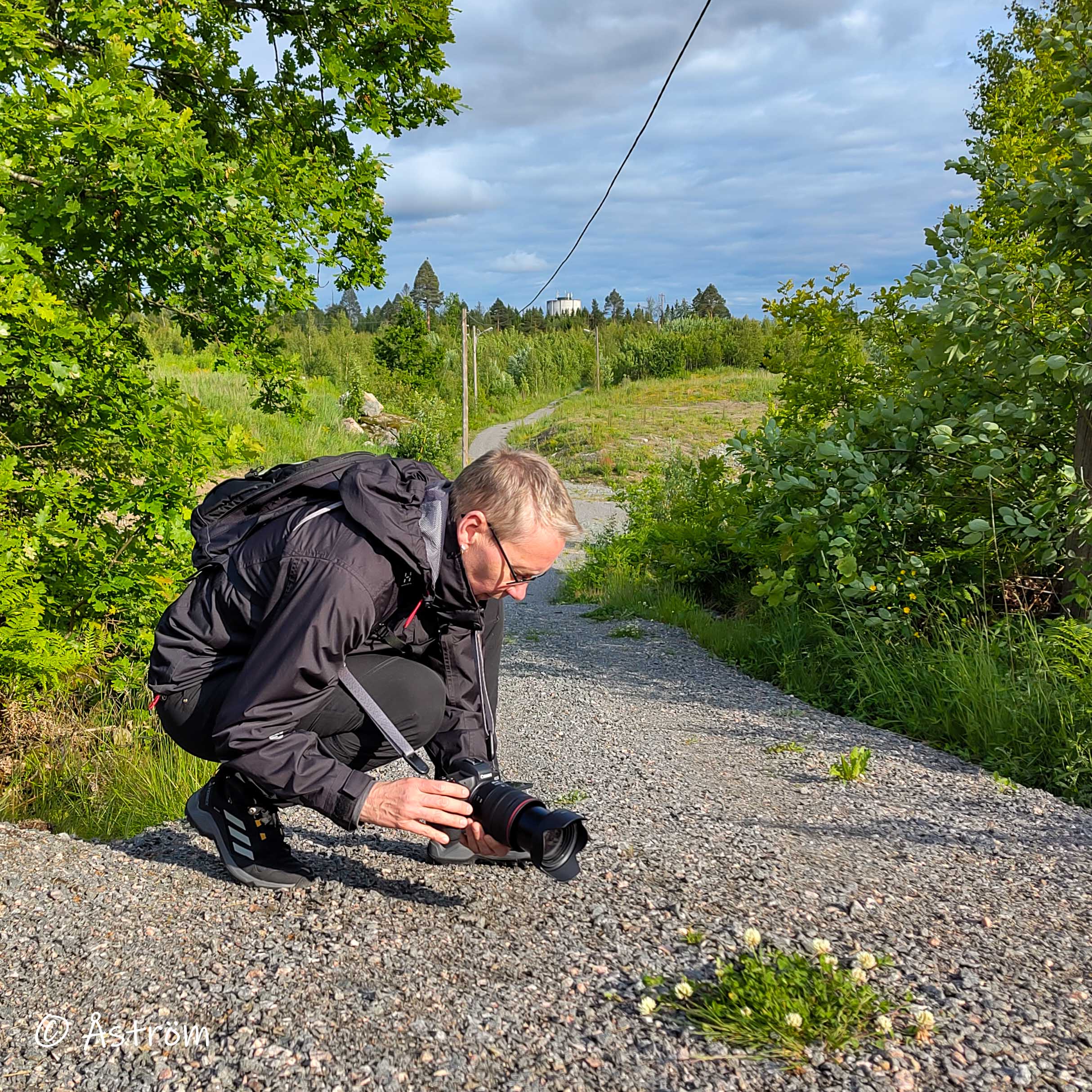 Jag sitter på huk med kameran redo att fotografera något på marken.